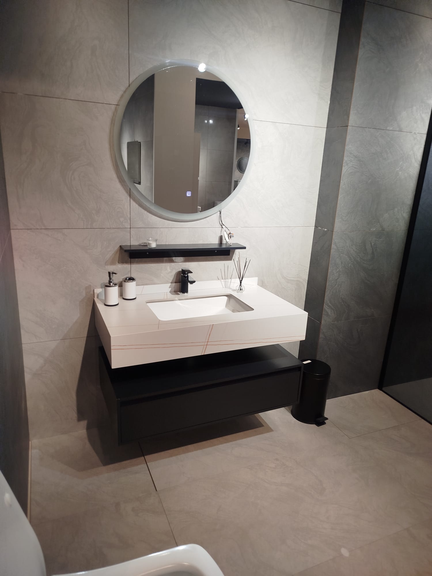 Moderna kupatilska oprema sa minimalističkim dizajnom, uključuje lavabo sa elegantnom podlogom i ogledalom uokvirenim u jednostavnom stilu.