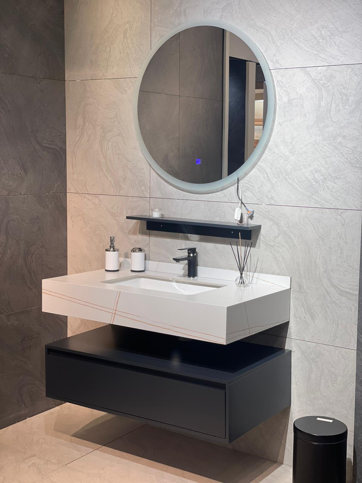 Moderna kupatilska oprema sa minimalističkim dizajnom uključuje elegantan lavabo sa savremenim slivnikom i okruglim ogledalom. Ovaj set pruža funkcionalnost i estetski privlačan izgled.