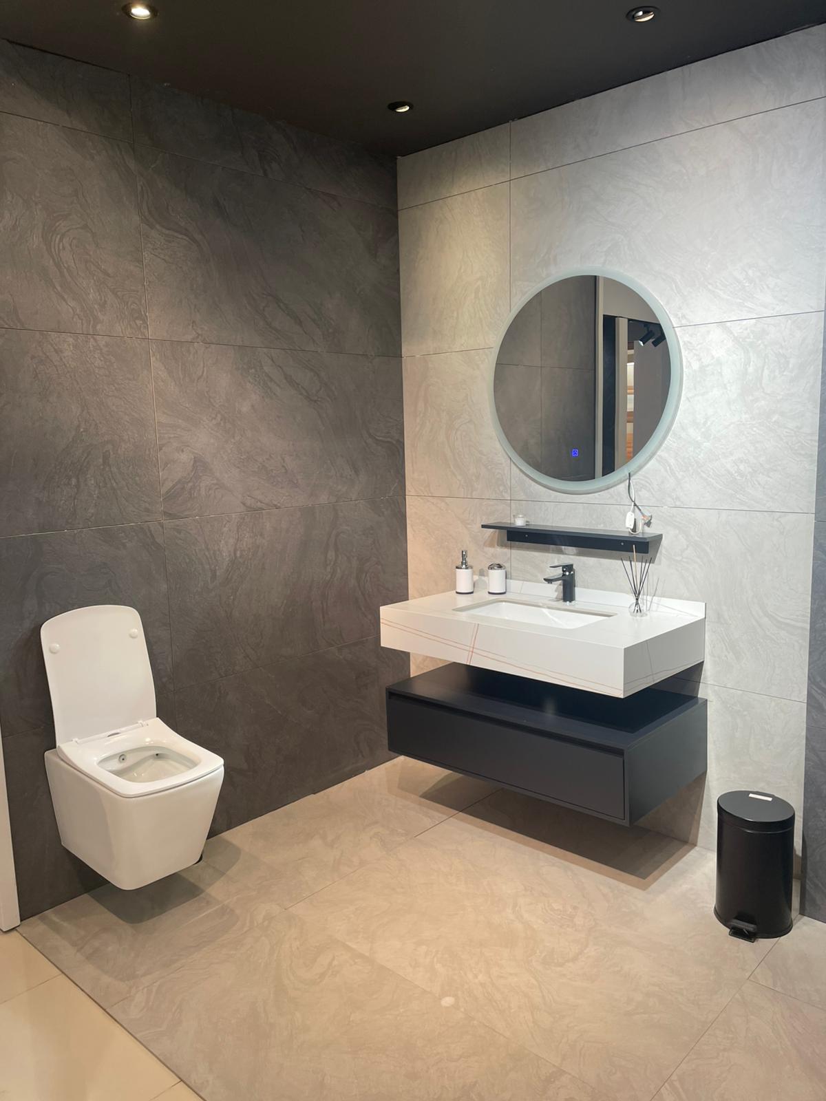 Moderno kupatilo sa elegantnim WC-om i minimalističkim lavabo namještajem. Osvetljenje i kombinacija boja doprinose savremenom izgledu prostora.