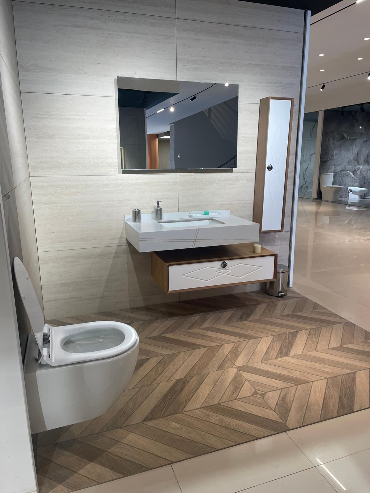 Moderno kupatilo sa elegantnim lavabo elementom i ogledalom, uz minimalistički dizajn i funkcionalne detalje. WC šolja je postavljena uz zid, čime se postiže čist i uredan izgled prostora.
