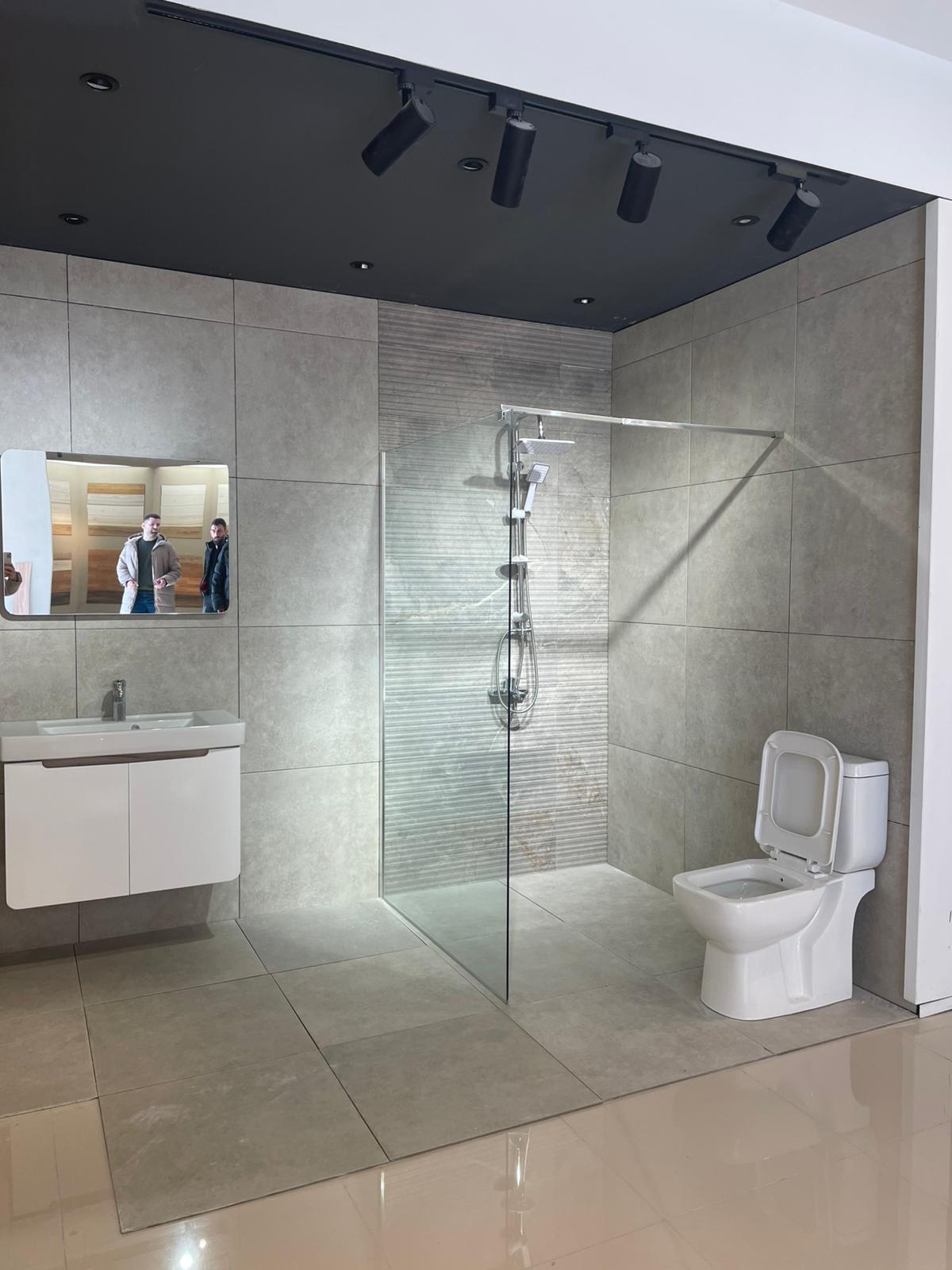 Moderno kupatilo sa elegantnom tuš kabinom, savremenim WC-om i minimalističkim lavabo ormarićem. Prostor je osvetljen i koristi prirodne tonove za stvaranje opuštajuće atmosfere.