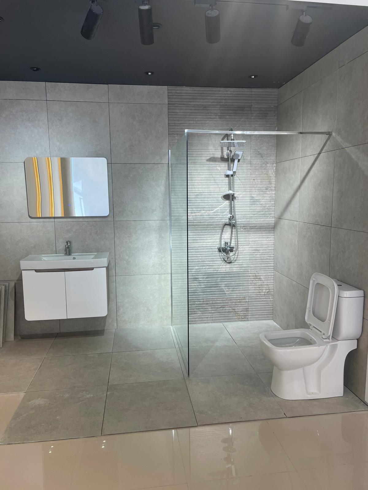 Moderno kupatilo sa elegantnom tuš kabinom od stakla, minimalističkim lavabo ormarićem i savremenim WC-om. Prostor je osvetljen prirodnom svetlošću i ima savremeni dizajn.