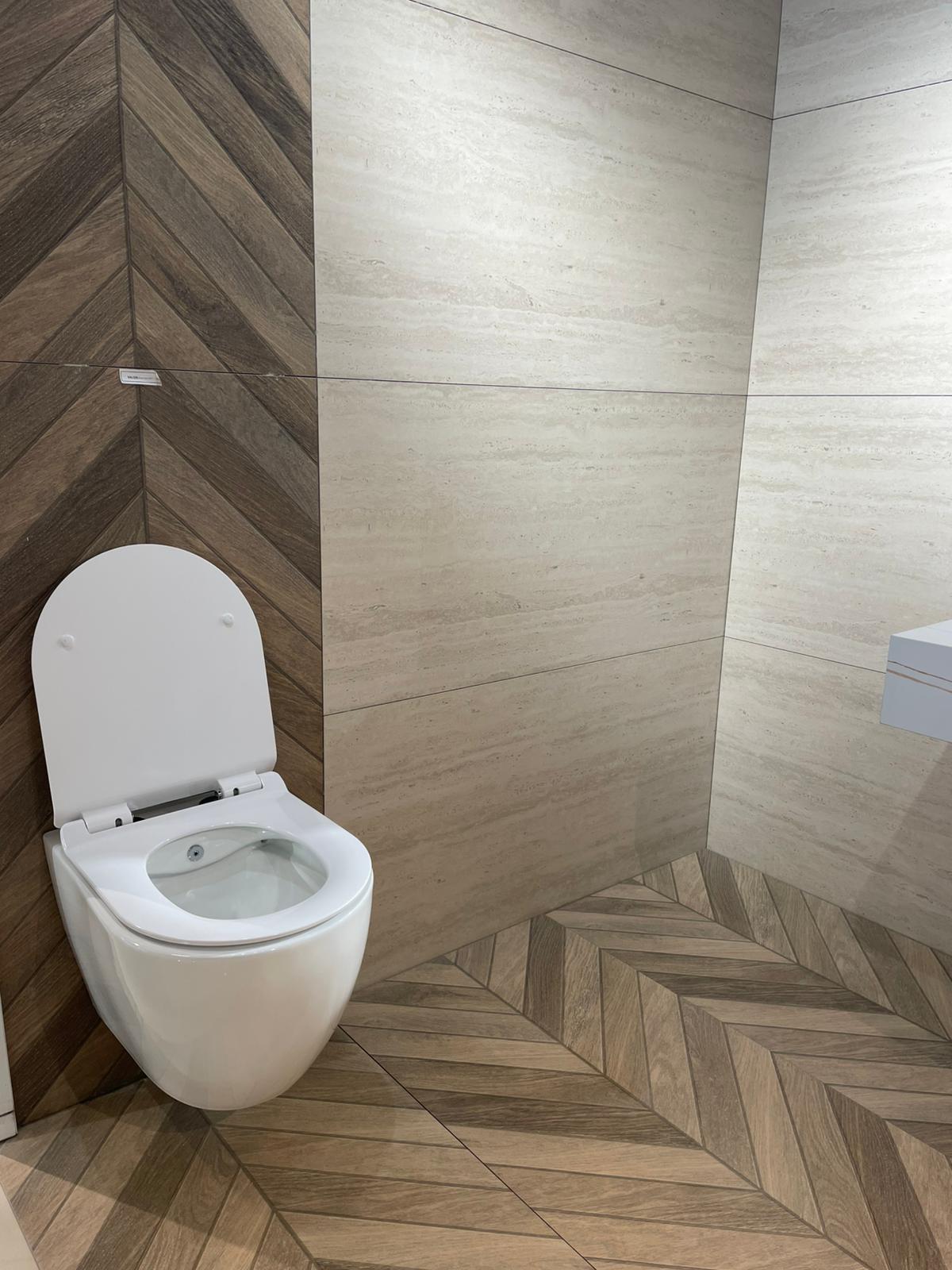 Moderna WC školjka sa čistim linijama, smeštena u prostoru sa elegantnim drvenim pločicama koje stvaraju toplu atmosferu.