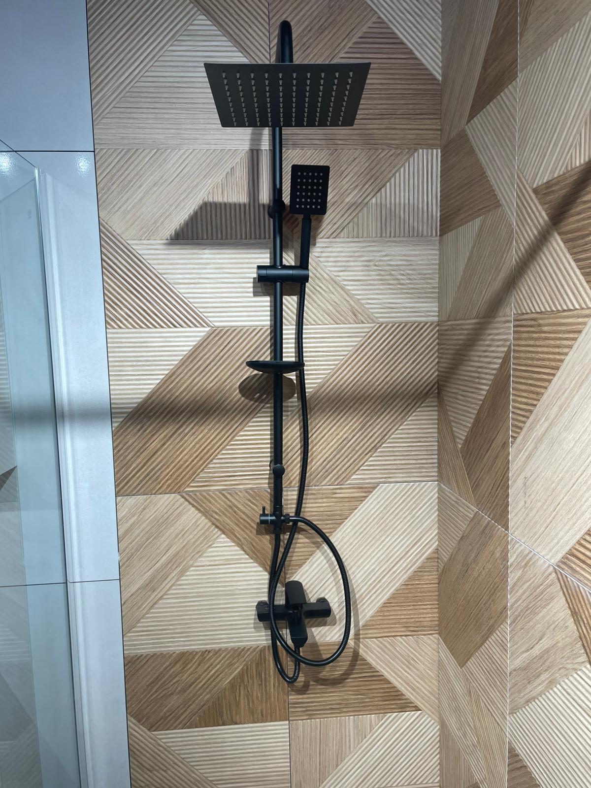 Moderna tuš kabina sa crnim baterijama i elegantnim dizajnom, koja se savršeno uklapa u enterijer sa drvenim pločicama.
