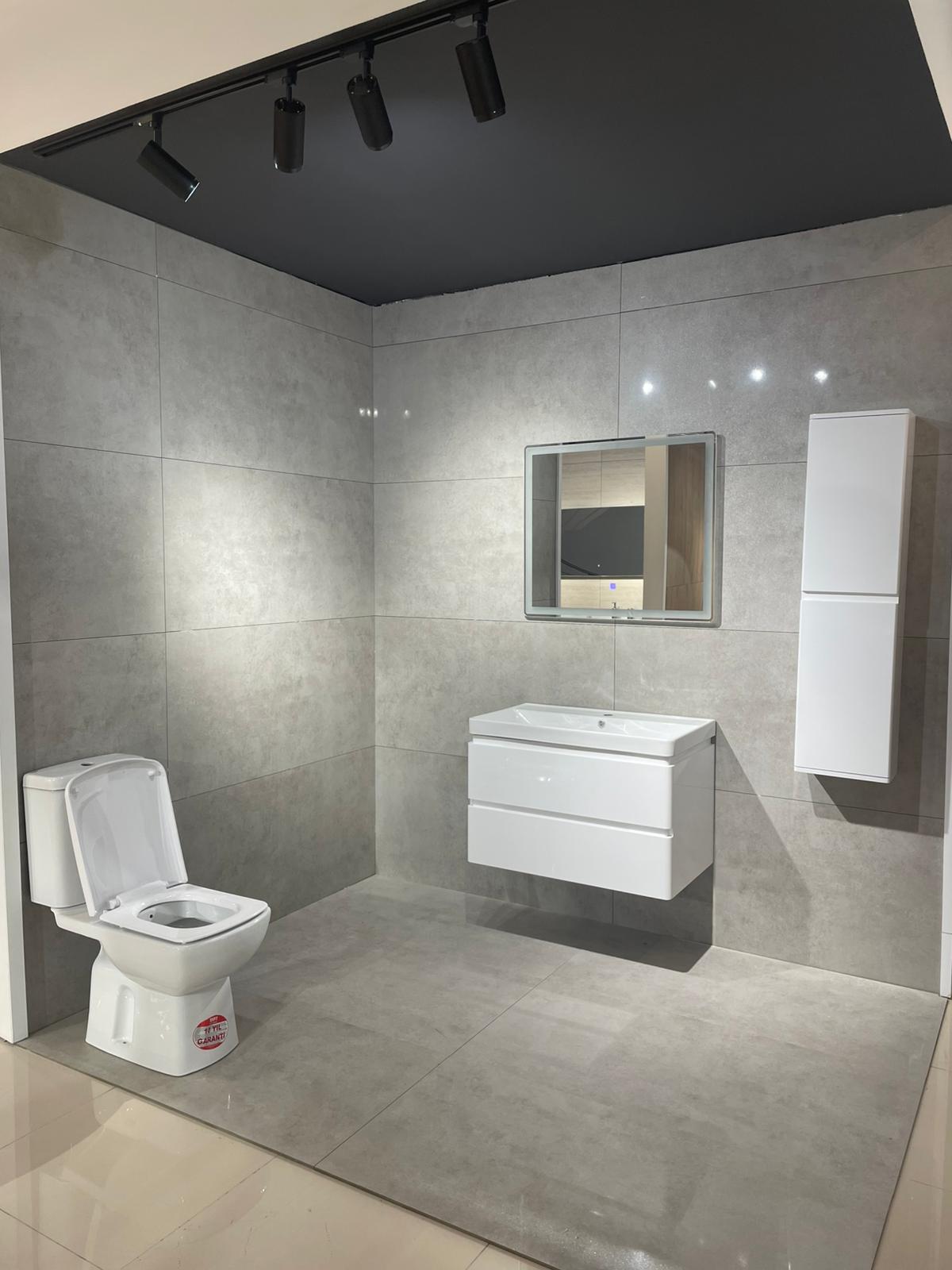 Moderno kupatilo sa elegantnom keramikom i minimalističkim dizajnom. Uključuje WC školjku, lavabo sa ormarićem i ogledalo, sve u neutralnim tonovima.
