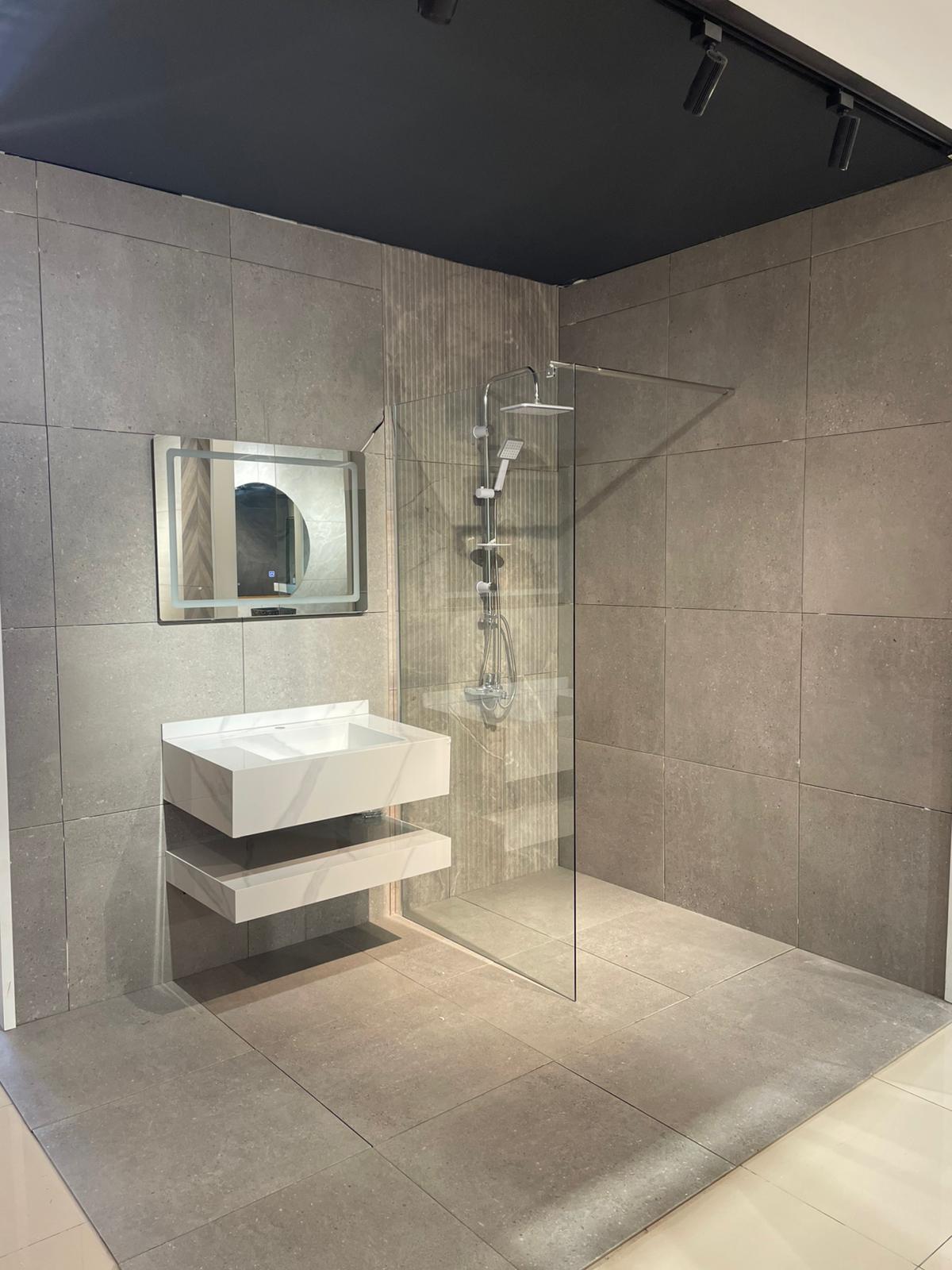 Moderno kupatilo sa minimalističkim dizajnom, uključuje staklenu tuš kabinu, elegantan lavabo sa policama i ogledalo.